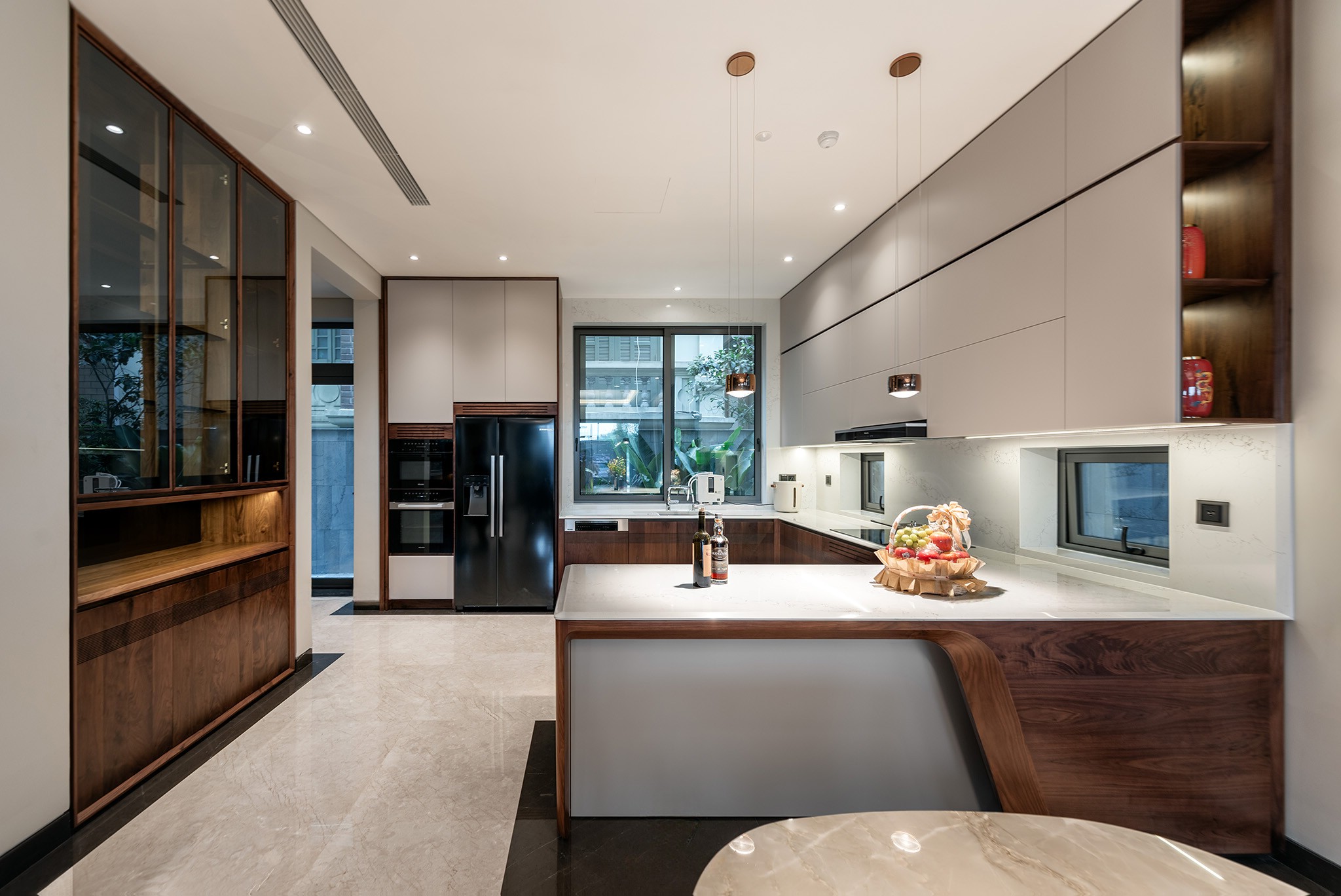 Thiết kế tủ bếp hiện đại chữ L với bàn bar gắn liền từ gỗ óc chó và acrylic trắng Thiết kế tủ bếp hiện đại chữ L với bàn bar gắn liền và tủ gỗ acrylic trắng kết hợp gỗ óc chó